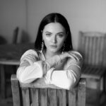 grayscale photo of woman in long sleeve shirt sitting on bench