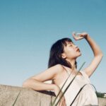 woman leaning on wall covering her face