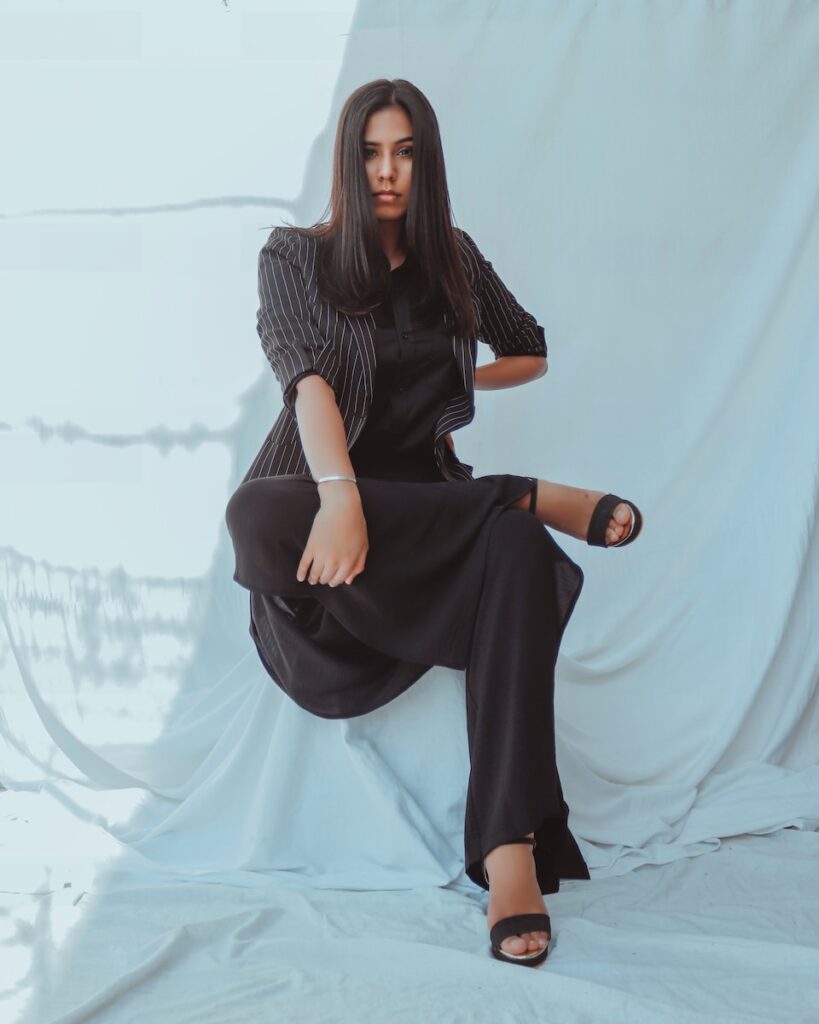 woman in black and white stripe long sleeve dress sitting on white textile