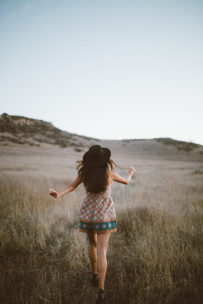 woman wearing brown and green floral romper walking on green grass