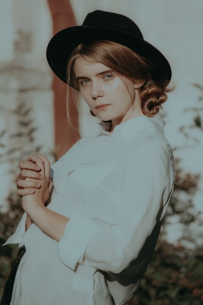 woman wearing white collared button-up long-sleeved shirt and black hat standing