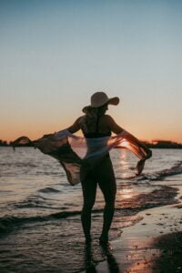 woman in black and white bikini wearing brown sun hat standing on beach during daytime