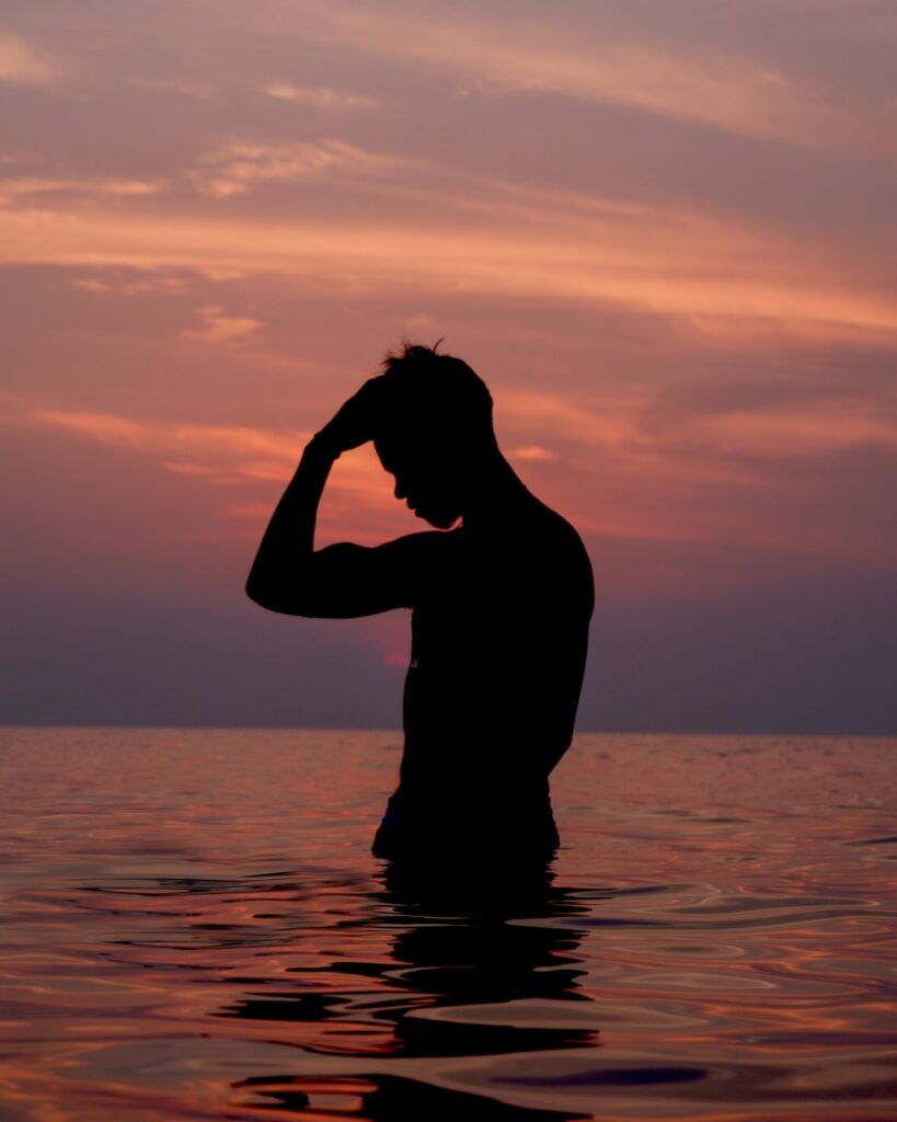 silhouette of woman on water during sunset