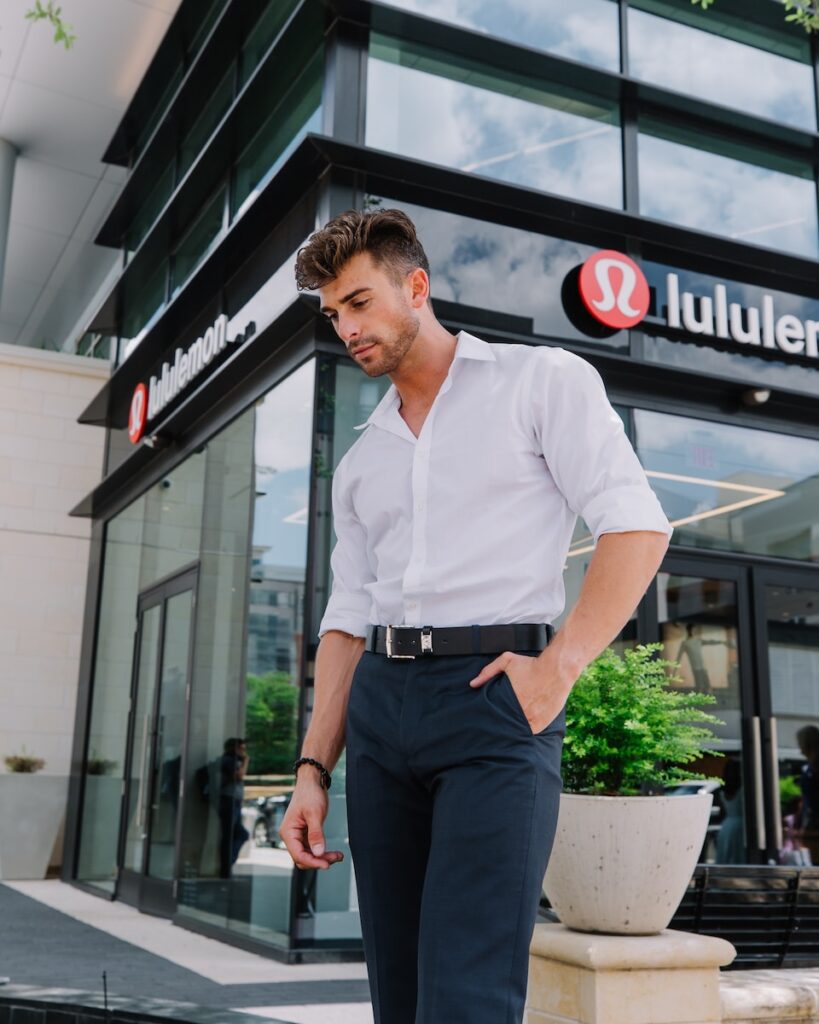 man in white dress shirt and black pants standing near glass window during daytime